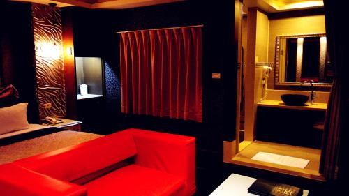 a bedroom with a red chair and a red curtain at Discovery Motel - Tucheng in Tucheng