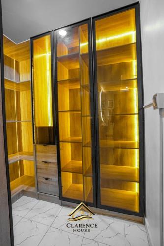 a glass closet with wooden shelves in a room at Clarence House in Ikeja