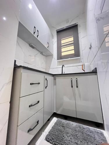 a white kitchen with a sink and a window at Studio apartment in Surulere in Lagos