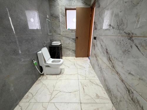 a bathroom with a toilet in a marble wall at Jawla Resort in Palwal