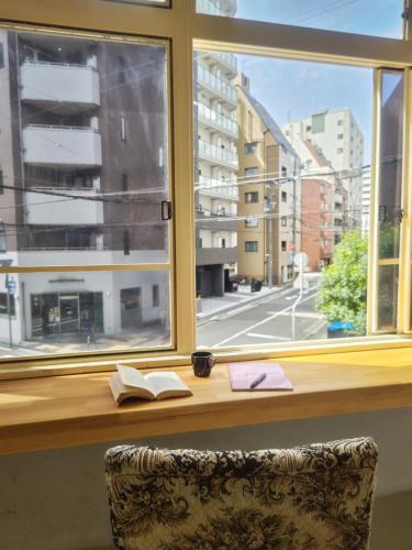 a desk with a window with a book at The hostel kobe in Kobe