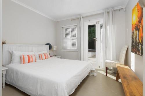 a white bedroom with a large bed and a window at Charming B&B in Somerset West