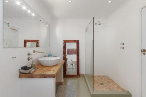 a white bathroom with a sink and a mirror at Charming B&B in Somerset West