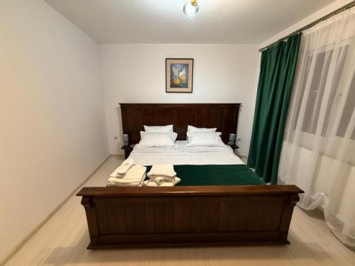 a bedroom with a large bed with green curtains at Vila Rhea in Caciulata