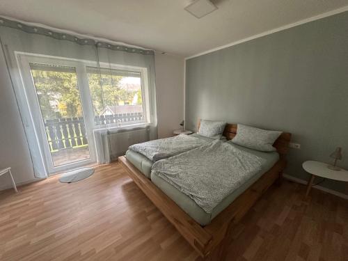 a bedroom with a bed and a large window at Ferienwohnungen Hoheeifel Nähe Nürburgring Platz für bis zu 10 Personen ,Verleih von zwei E-MTB möglich in Kelberg
