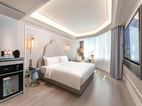a bedroom with a white bed and a large window at Mercure Xi'an High-tech Zone Center in Xi'an