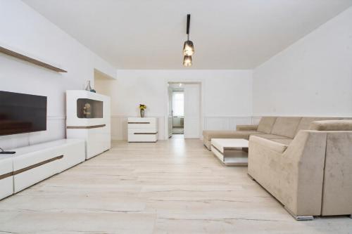 a white living room with a couch and a tv at Danubia Apartment Gabčíkovo in Gabčíkovo