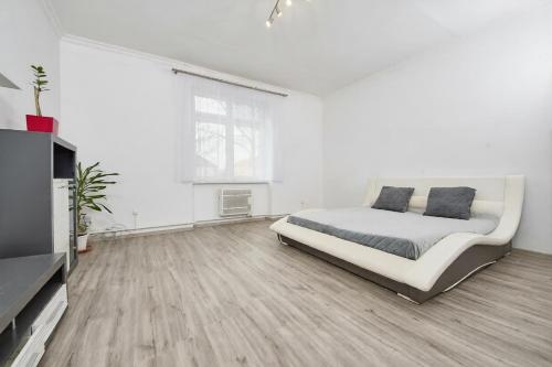 a white bedroom with a bed and a television at Danubia Apartment Gabčíkovo in Gabčíkovo
