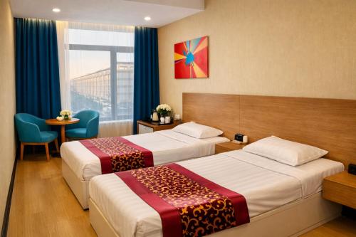 a hotel room with two beds and a window at Ochir Hotel in Ulaanbaatar