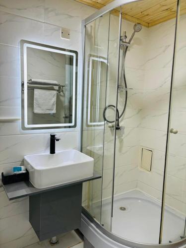 a white bathroom with a sink and a shower at Ochir Hotel in Ulaanbaatar