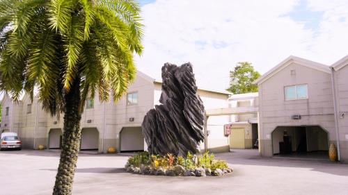a statue in front of a building with a palm tree at Discovery Motel - Tucheng in Tucheng