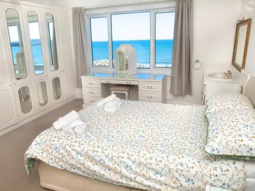 a bedroom with a bed and a desk and window at Weymouth Bay Apartment C in Weymouth