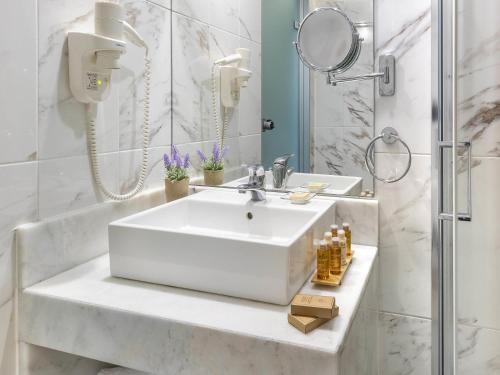 a white bathroom with a sink and a shower at Mercure Rhodes Alexia Hotel & Spa in Rhodes Town