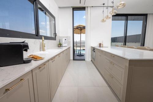 a large kitchen with white counter tops and windows at רויאל בוטיק טווינס 2 in Safed