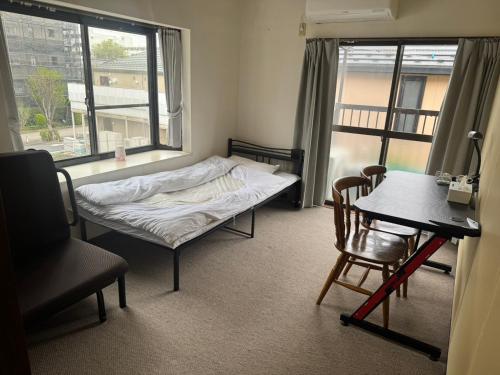 a bedroom with a bed and a desk and a table at YCS2 Guest house, good access to Shinjuku in Nishitokyo