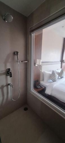 a bedroom with a window with a bed and a shower at Hotel Regalia in Bathinda