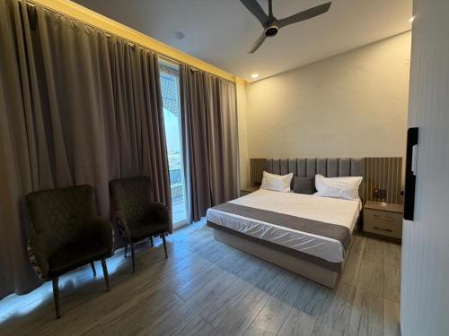 a bedroom with a bed and two chairs and a window at Jawla Resort in Palwal