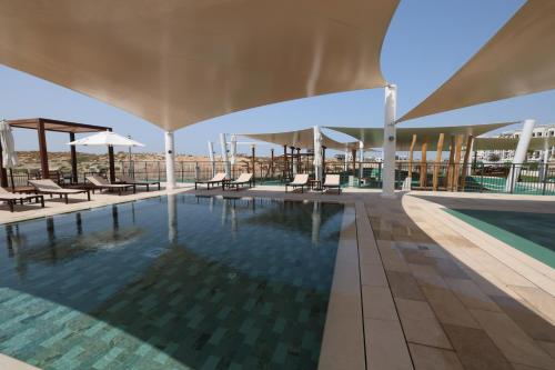 a swimming pool with chairs and umbrellas on a building at Luxury Yas Golf Studio Next to Yas Parks in Abu Dhabi