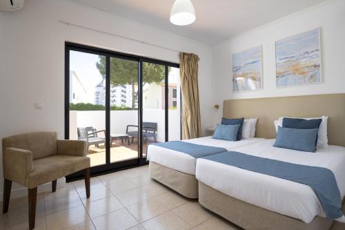 a bedroom with a bed and a chair and a window at Mouraliz Apartments by HD PROPERTIES - Vilamoura Marina in Vilamoura