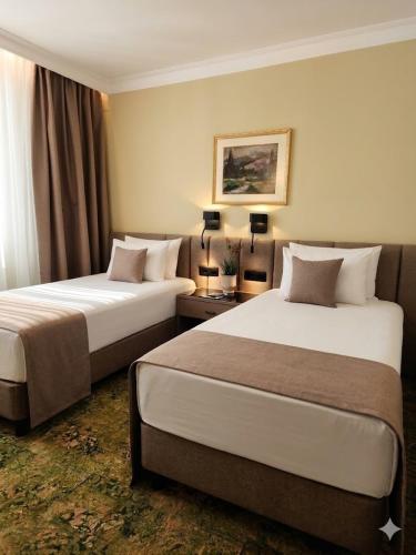 a hotel room with two beds and two lamps at Hotel Turist - City Center in Skopje