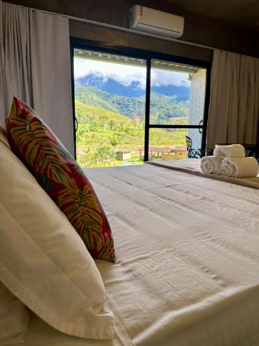 a bedroom with a large bed with a large window at Hospedagem Terras Raras Patrimônio da Penha in Divino de São Lourenço