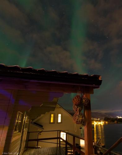 a house with the aurora dancing in the sky at Furoy Hotel Apartments and Boating in Sorreisa