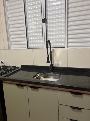 a kitchen counter with a sink and two windows at Kitnet bem equipada para 2 pessoas in Curitiba