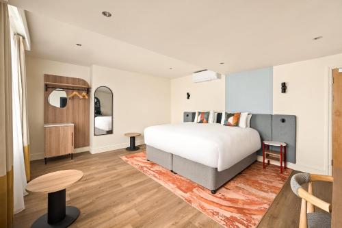 a bedroom with a large bed and a table at voco London - Bloomsbury by IHG in London