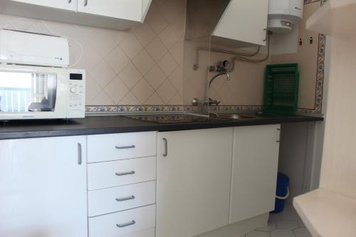 a kitchen with white cabinets and a microwave at Praia Rocha Balcony First Line Beach View Studio in Praia da Rocha