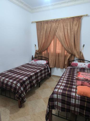 two beds in a room with a window at nayla y amira in Martil
