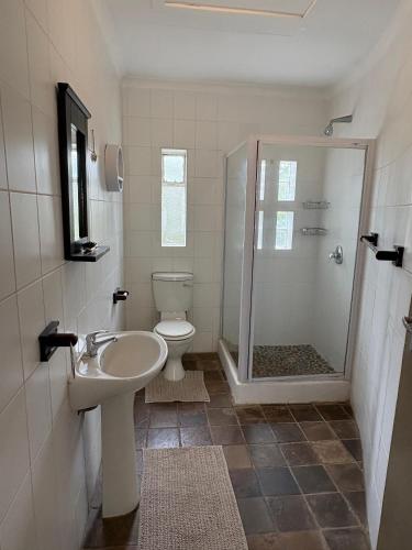 a bathroom with a toilet and a sink and a shower at Cornerstone on Livingstone in Vryburg