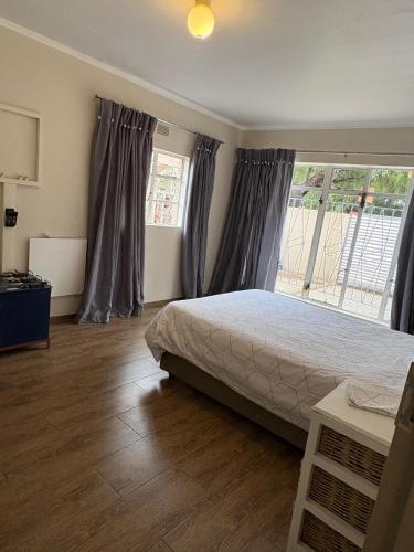 a bedroom with a bed and a large window at Cornerstone on Livingstone in Vryburg