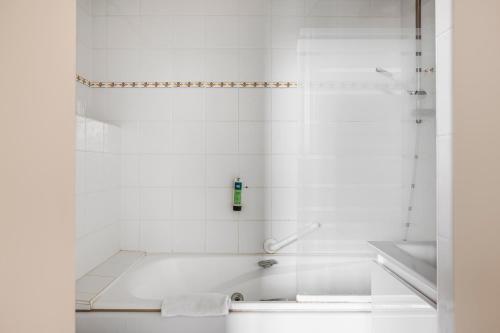 a white bathroom with a tub and a sink at Logis Hôtel Restaurant Cristal in Saumur