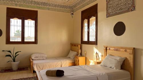 a bedroom with two beds and two windows at Tidmi Wave Anza in Agadir