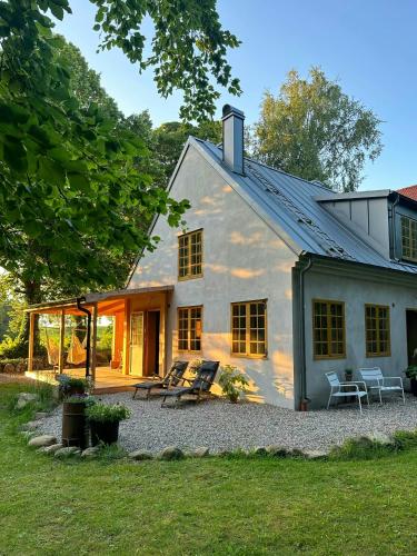 a white house with a porch and a patio at Designed House With Recycled Details In Österlen in Köpingebro