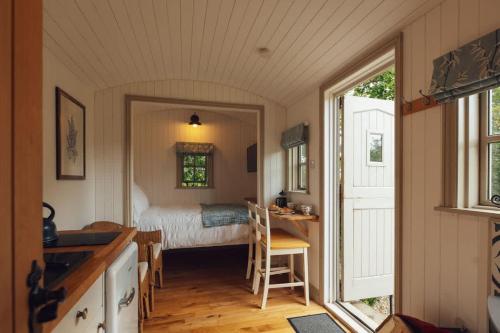 a bedroom with a bed and a table and a desk at Shepherd's Hut - Jasmine in Haverfordwest