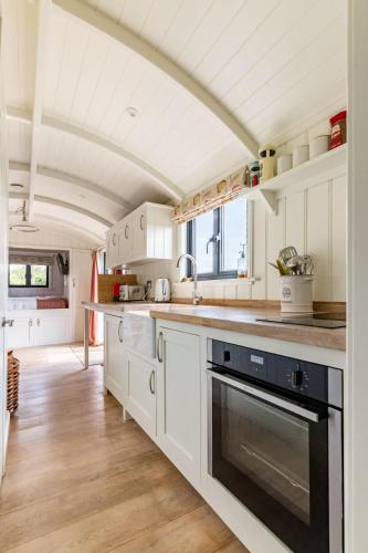 a kitchen with white cabinets and a sink at Unique Double Shepherd's Hut Hideaway - Pembrokeshire in Haverfordwest