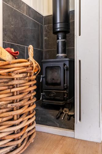 a wood stove in a bathroom with a basket at Unique Double Shepherd's Hut Hideaway - Pembrokeshire in Haverfordwest