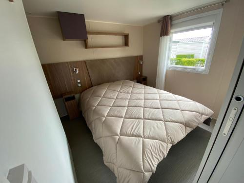 a bedroom with a white bed with a window at Camping Les 2 Plages in Quend