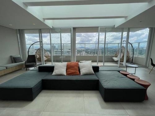 a living room with a large couch in front of windows at 1412 - Studio completo com varanda e vaga in São Paulo