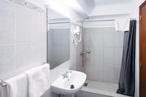 a white bathroom with a sink and a shower at Murças74 - Studio Apartments in Funchal
