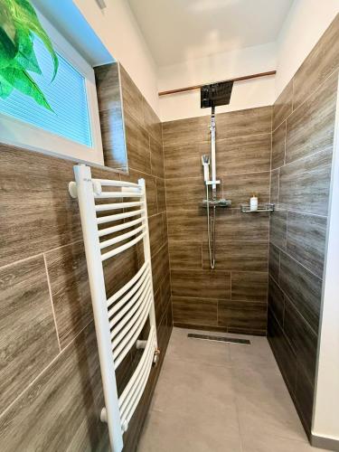 a bathroom with a shower with wooden walls at Local-Lux Garden Residence A- 2 Bedrooms-Terrace in Kecskemét