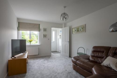 a living room with a couch and a television at Cosy 3 Bed Near Beaches, Cardiff & Brecon Beacons in Coity