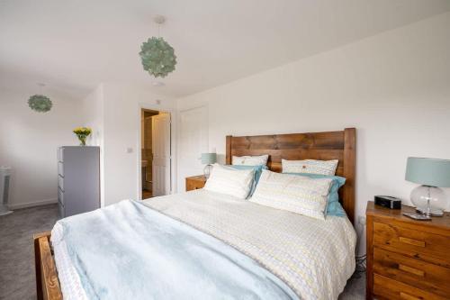 a bedroom with a large bed with a wooden headboard at Cosy 3 Bed Near Beaches, Cardiff & Brecon Beacons in Coity