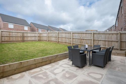 a patio with a table and chairs and a fence at Cosy 3 Bed Near Beaches, Cardiff & Brecon Beacons in Coity