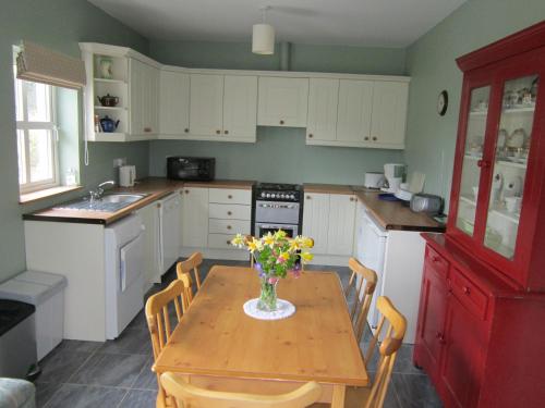 a kitchen with a table with a vase of flowers on it at Feirm Cottage in Kenmare