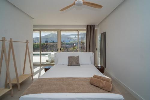 a bedroom with a white bed with a ceiling fan at Villa James by Aura Collection in Tindaya