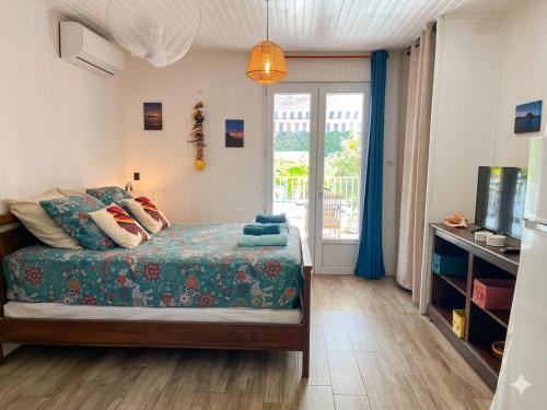 a bedroom with a bed and a tv and a window at Studio accès piscine, plage à 50m in Le Gosier
