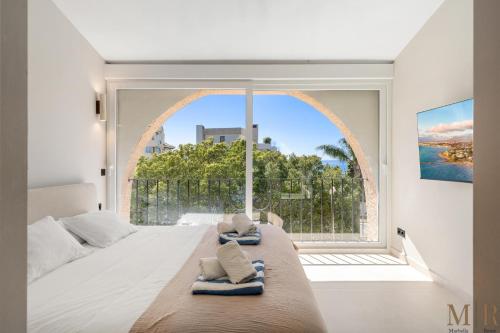 a bedroom with a large window with towels on a bed at Casa Eva Ref #97 in Estepona