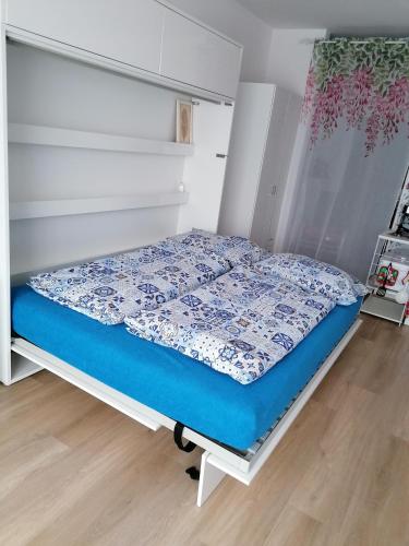 a bed with a blue comforter in a room at Apartmán Alicante in Dunajská Streda